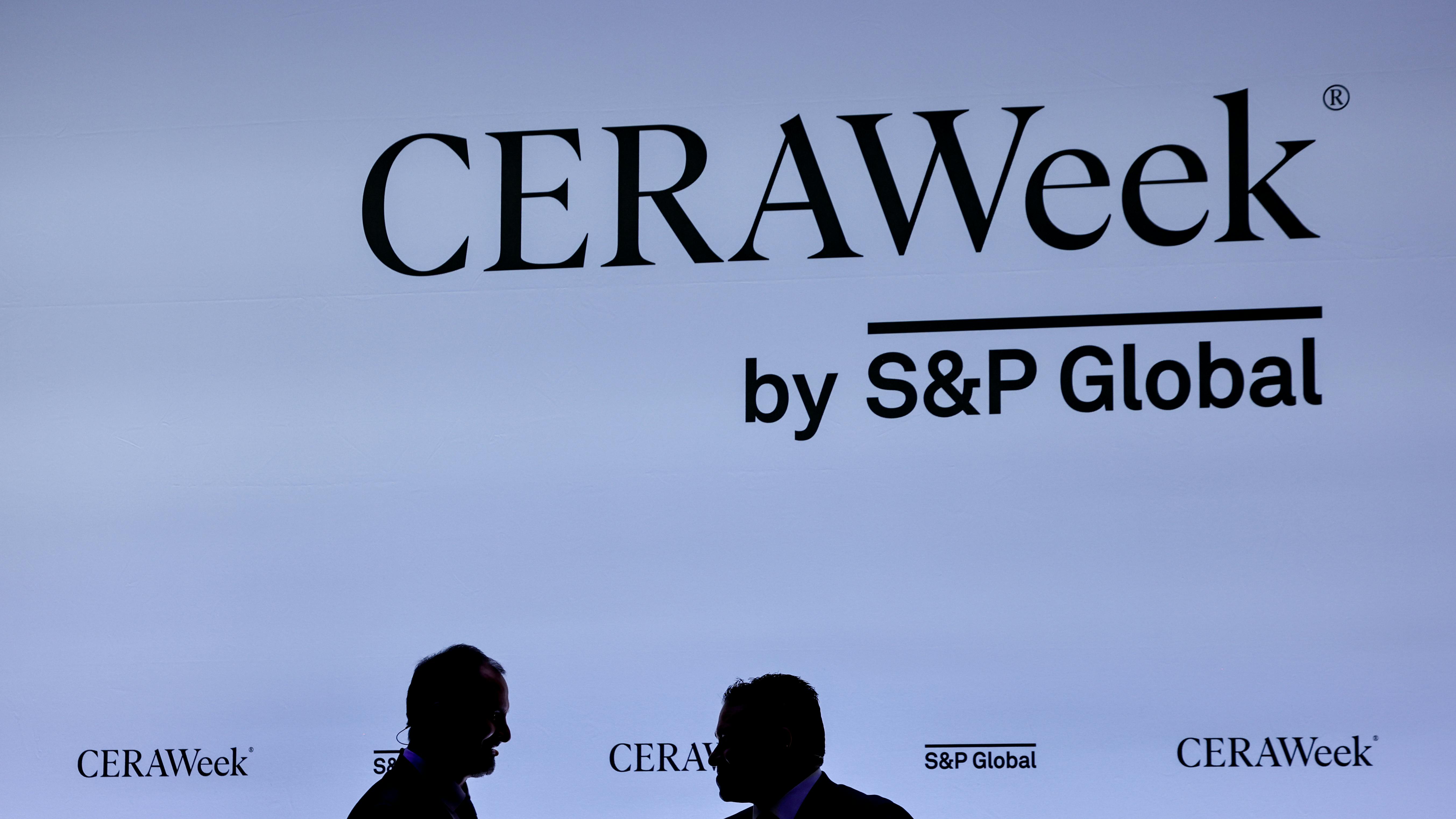 two CERAWeek attendees in silhouette in front of CERAWeek logo backdrop
