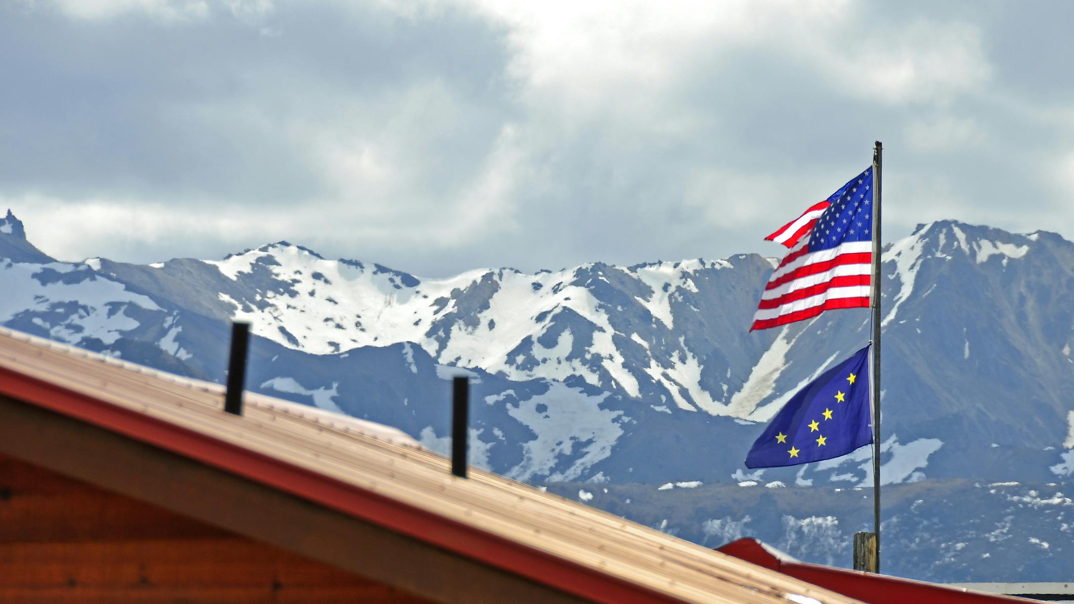 American and Alaskan flag fly atop a building in the mountains of Denali