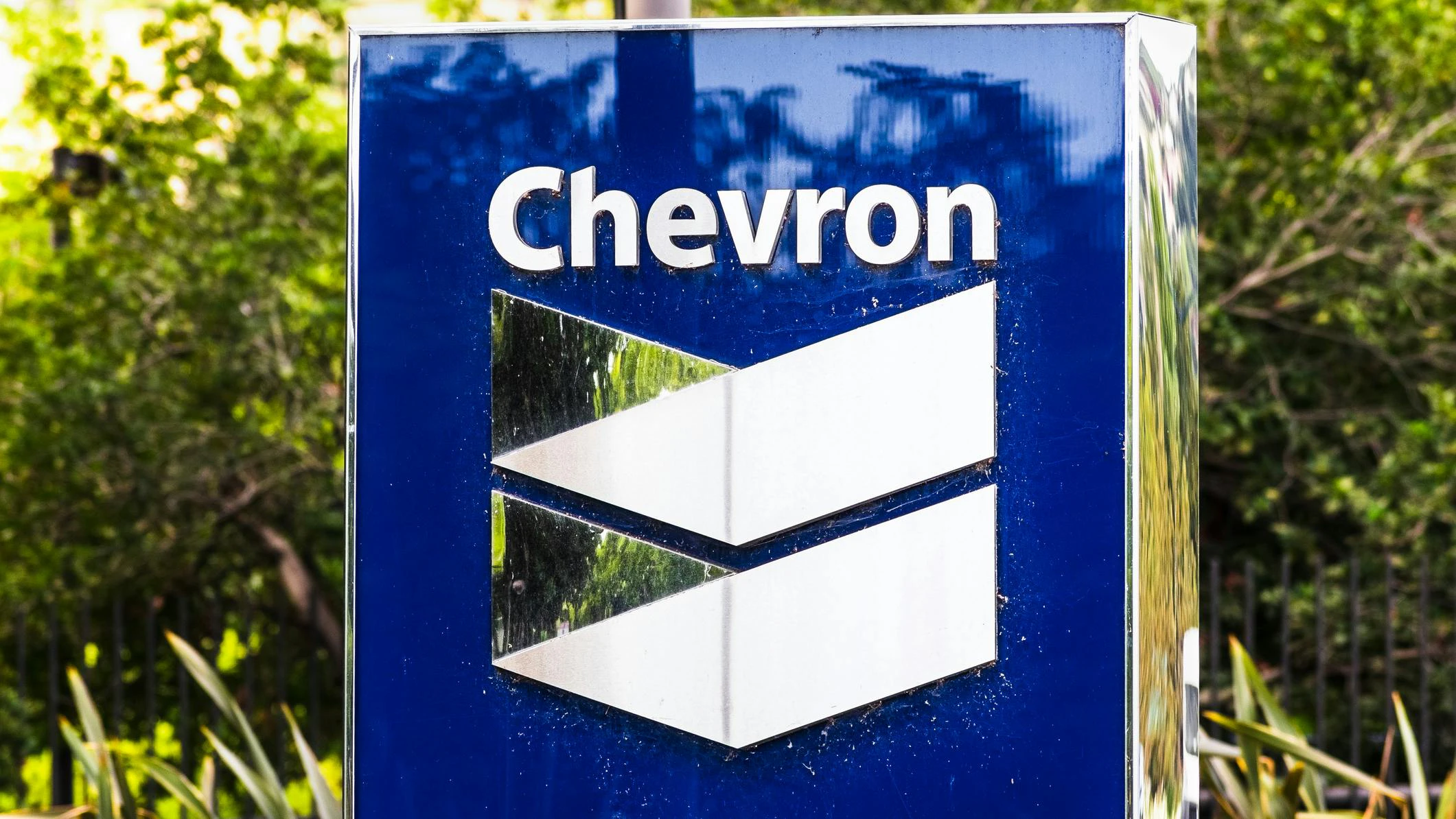Chevron logo on sign with bushes in background