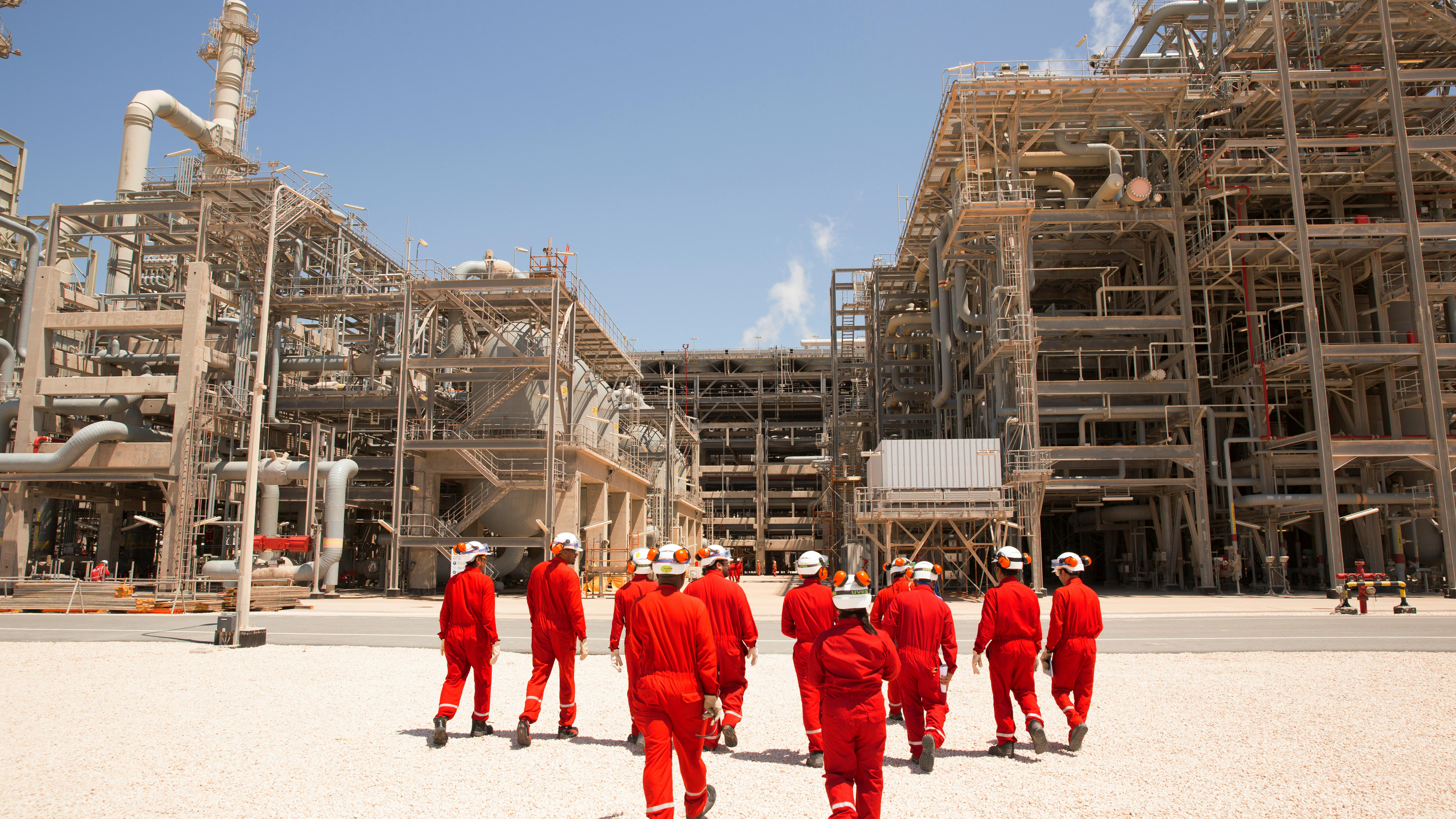 Workers walking in front of oil and gas infrastructure