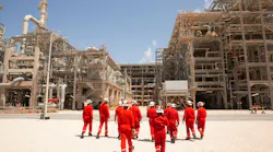 Workers walking in front of oil and gas infrastructure Workers walking in front of oil and gas infrastructure