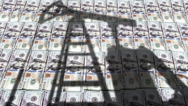 Shadow of oil and gas drilling equipment with picture of US currency in background