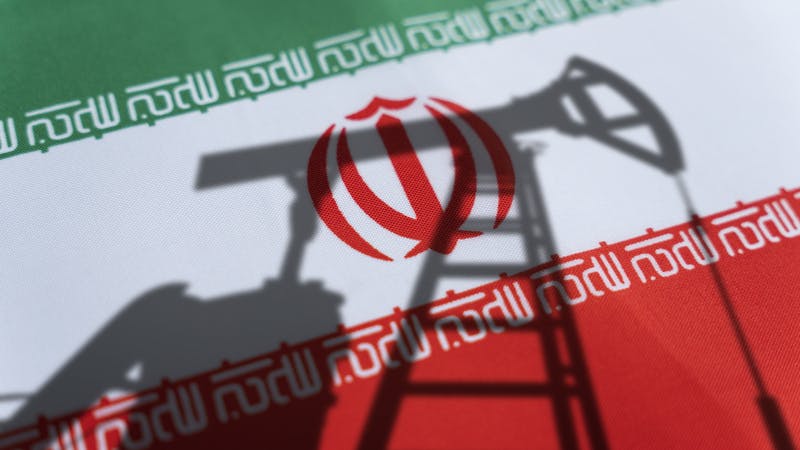 Shadow of oil and gas drilling equipment with Iran flag background