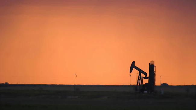 Silhouette of active oil pump shot at sunset