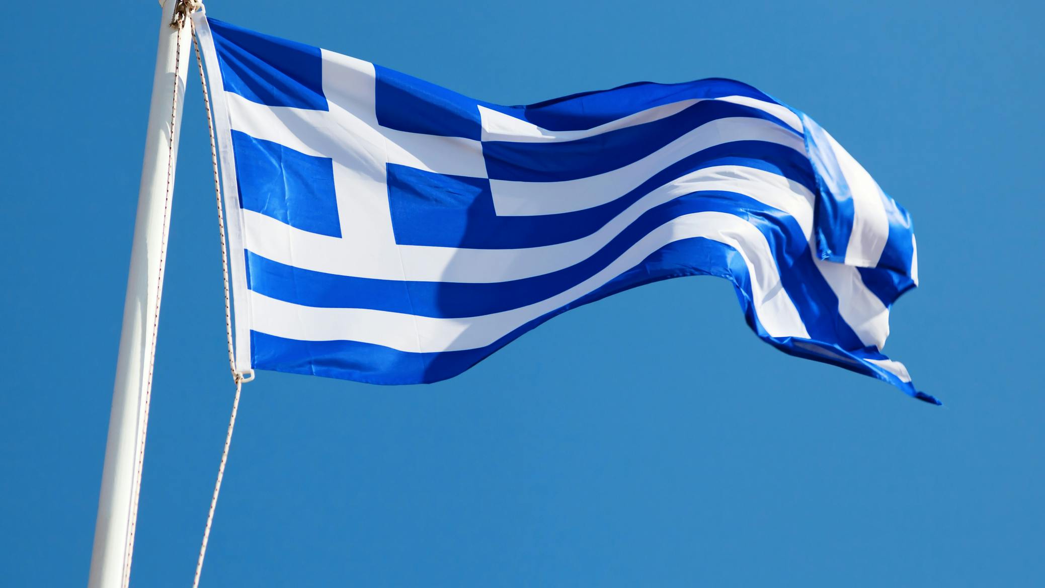 Greece flag waving in front of a blue sky