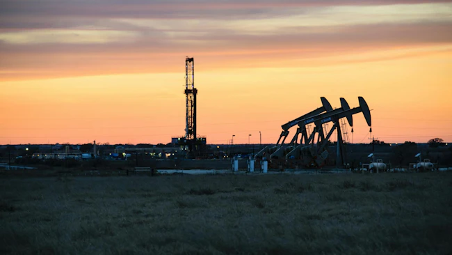 Oil and gas drilling rig, pump jack in front of sunset sky