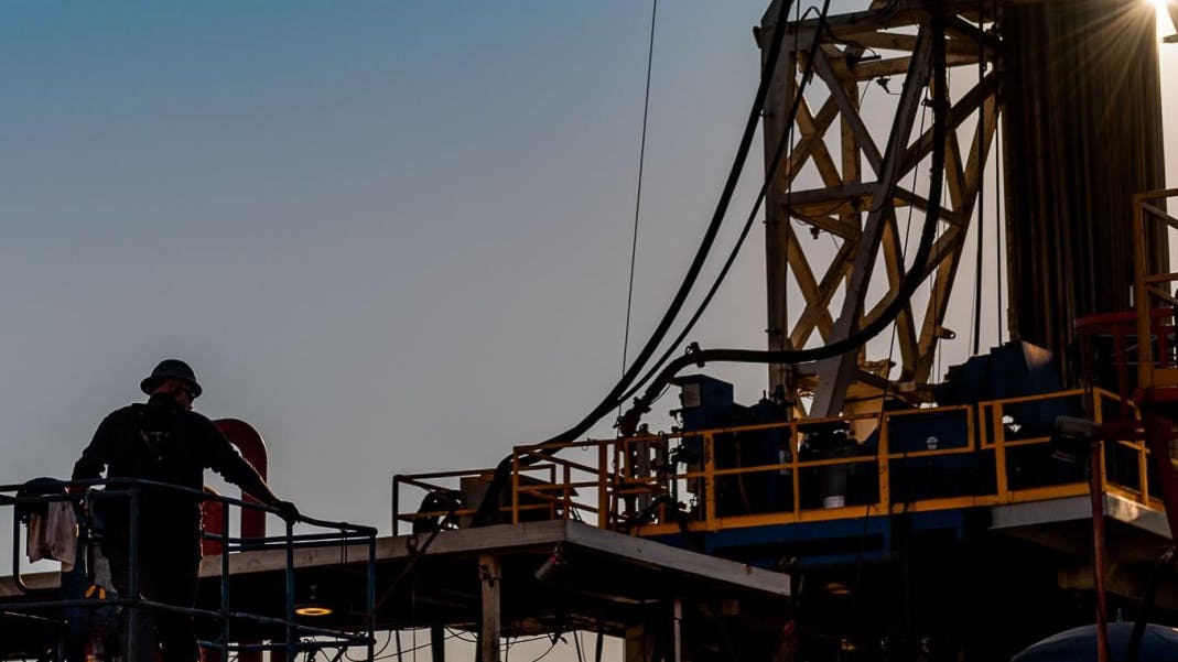 Silhouette of oil and gas rig worker in front of a rig.