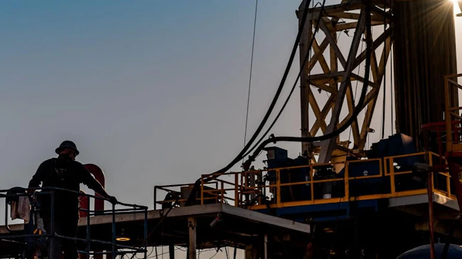 Silhouette of oil and gas rig worker in front of a rig.