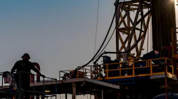 Silhouette of oil and gas rig worker in front of a rig.