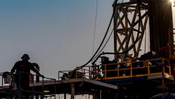 Silhouette of oil and gas rig worker in front of a rig.
