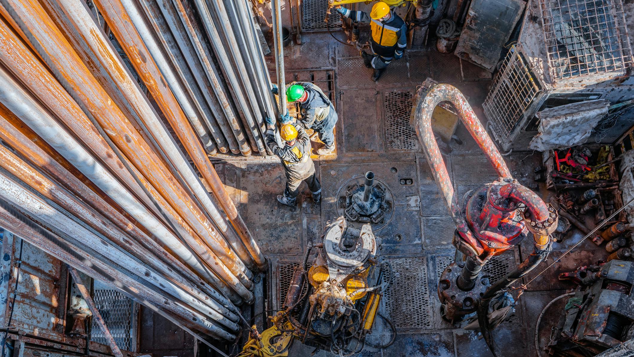 Offshore oil rig worker preparing equipment at wellhead platform.