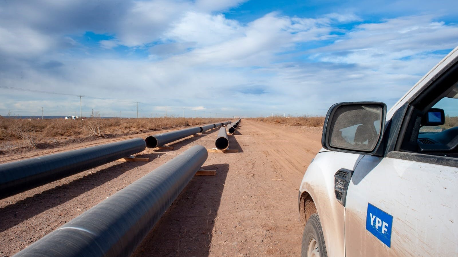 Pipe lay onshore Argentina as part of natural gas pipeline construction project. YPF-branded truck parked to the right.