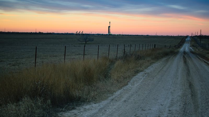 Shale oil rig and pumpjack at sunset in the distance.