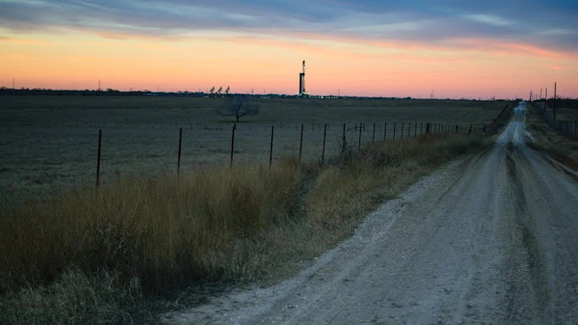 Shale oil rig and pumpjack at sunset in the distance.