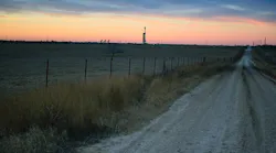 Shale oil rig and pumpjack at sunset in the distance.