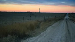 Shale oil rig and pumpjack at sunset in the distance.