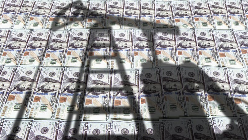 Shadow of oil pumpjack over stacks of US$100 bills