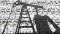 Shadow of oil pumpjack over stacks of US$100 bills