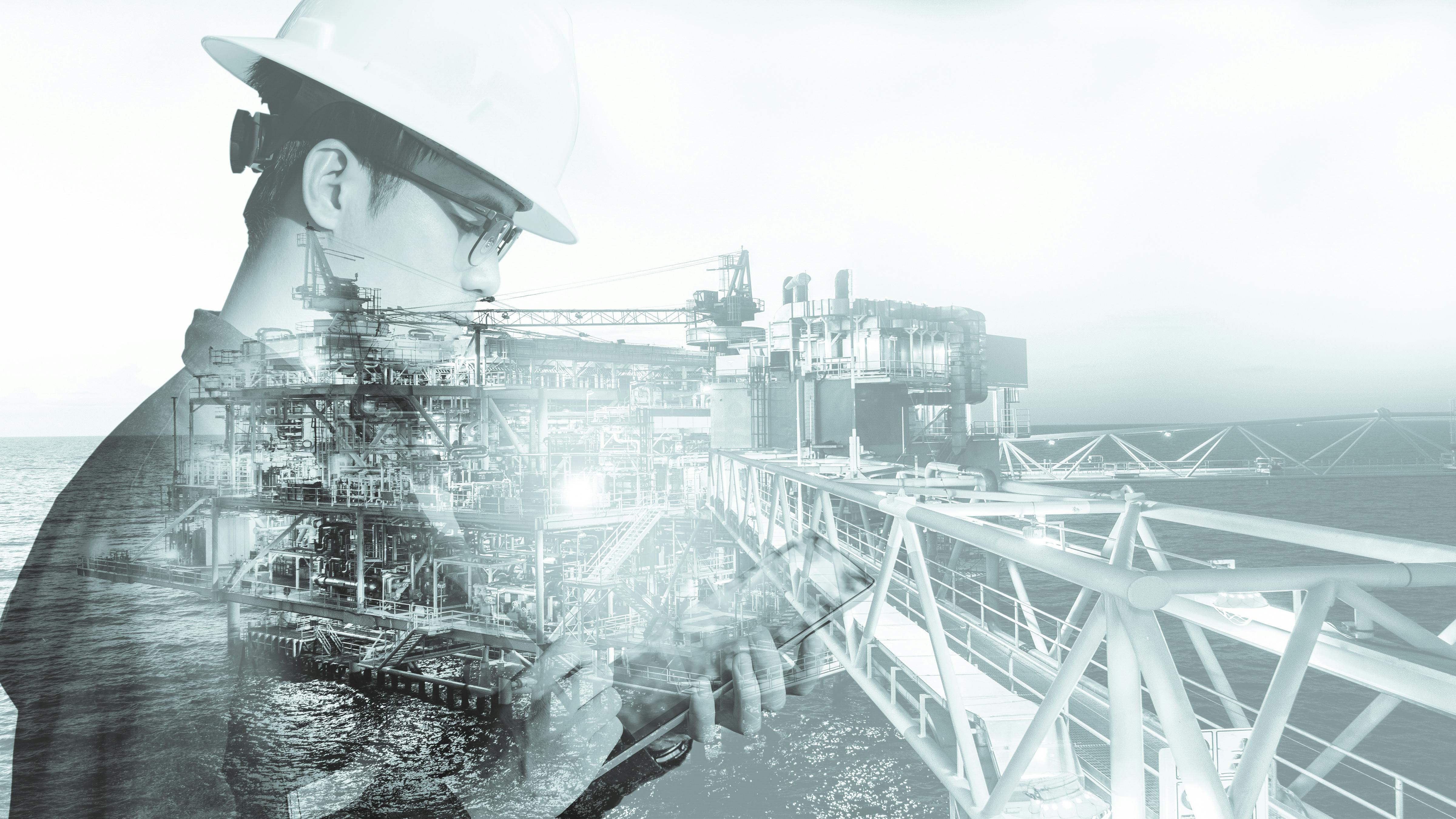 Double exposure of engineer with safety helmet and tablet. Offshore platform in background.