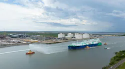 Tanker containing first shipment from the Golden Pass LNG project is guided by tug vessels through a canal waterway out to open sea.