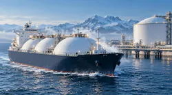 An LNG tanker passes through waters in front of a snowy terminal with snow-capped mountains in the background.