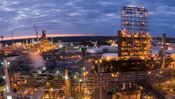 A nightime aerial view of Valero Refining New Orleans LLC’s 340,000-b/d St. Charles refinery in Norco, La., showing illuminated refining installations beneath a cloudy bluish-pink twilight sky.