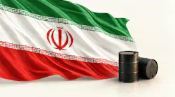 Iranian flag fluttering against a background of white behind two oil barrels.