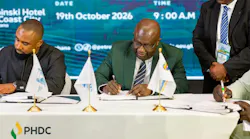 Signing ceremony for MOU to develop the second phase of PHDC's three-phased downstream petroleum showing two men at a table signing documents in front of blue-and-white banner background.