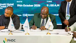 Signing ceremony for MOU to develop the second phase of PHDC's three-phased downstream petroleum showing two men at a table signing documents in front of blue-and-white banner background.