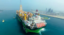 Large floating oil and gas production, storage and offloading vessel shown near the coastline escorted by smaller vessels